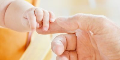 IVF baby holding its father's finger