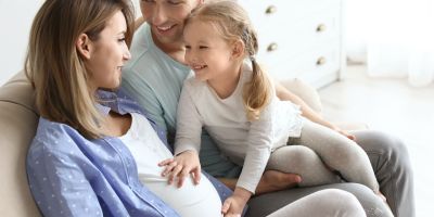 Dad with pregnant mom after IVF treatment and daughter feeling baby kick