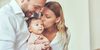 parents holding and kissing their baby