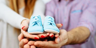 Expecting couple holding light blue baby shoes
