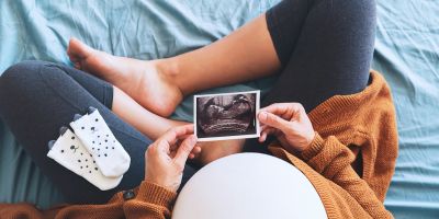 Pregnant Kingwood IVF mom admiring her bump and picture from her ultrasound
