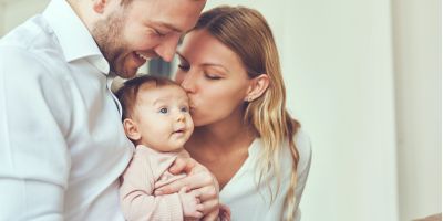 parents holding and kissing their baby
