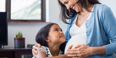 Daughter touching her mom's belly while mom is pregnant after North Houston IVF treatment