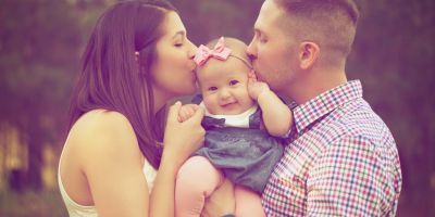 Couple holding and kissing their baby after successful IUI fertility treatment at our Kingwood and The Woodlands fertility clinics